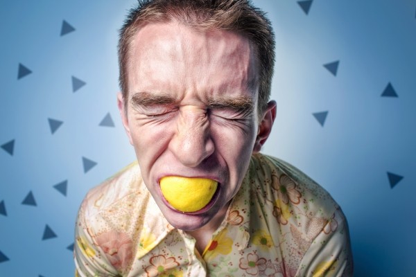 man-with-eyes-closed-and-lemon-in-mouth